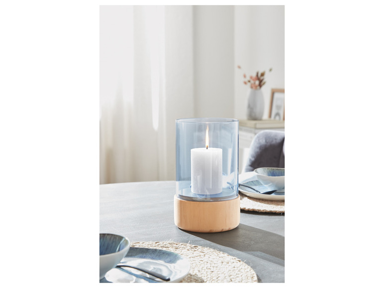 Un bougeoir en verre bleu avec un socle en bois sur une table