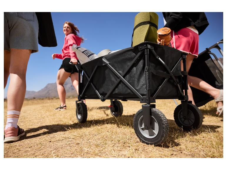 Chariot de camping pliable rempli d'équipement, tiré par des personnes en extérieur.