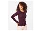 Femme en t-shirt bordeaux côtelé à manches longues et pantalon clair.