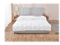 Une couette blanche à motif matelassé sur un lit gris moderne.