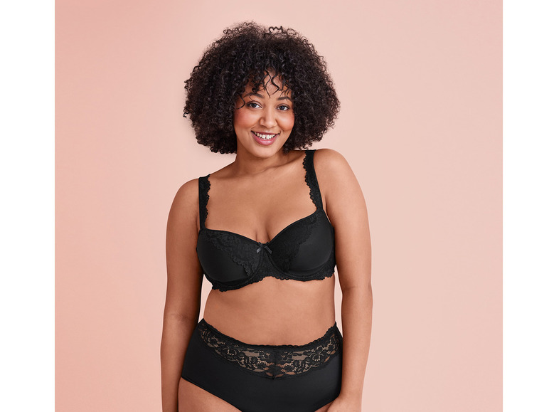 Une femme porte un soutien-gorge et une culotte noirs en dentelle.
