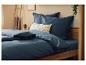 Parure de lit bleu marine sur un lit en bois avec coussins décoratifs et plantes.