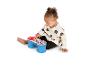 Un bébé joue avec une batterie de jouet bleue et rouge sur fond blanc.