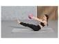 Femme faisant des exercices sur un tapis de yoga avec un petit ballon.