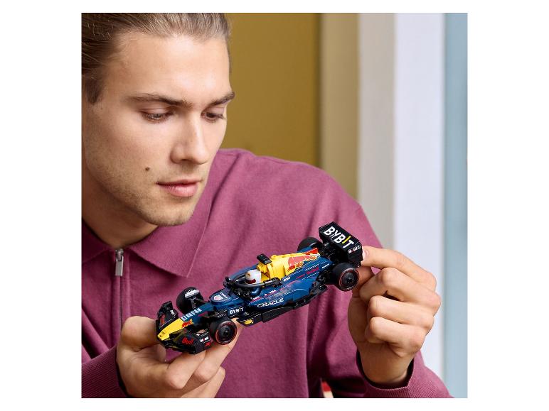 Un homme tient une voiture de course de Formule 1 Lego Red Bull Racing.