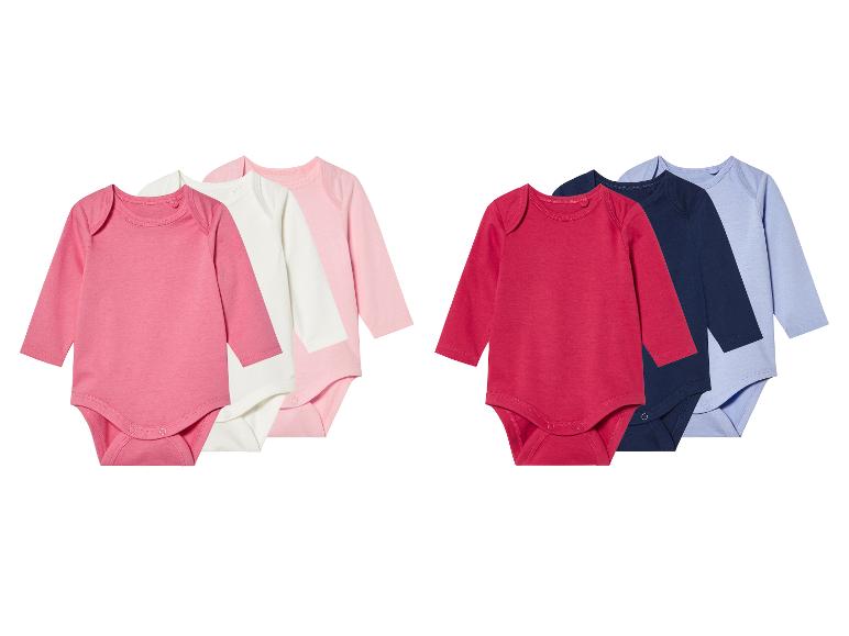 Trois bodys manches longues pour bébé dans des couleurs douces.