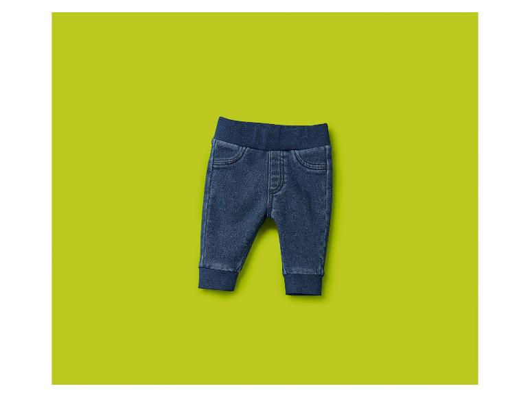 Une paire de jeans bébé bleu foncé sur un fond vert lime.