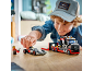 Garçon jouant avec un camion transporteur de voitures de course et une voiture de course jouets.