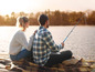 Un couple assis sur une jetée à pêcher avec une canne à pêche.