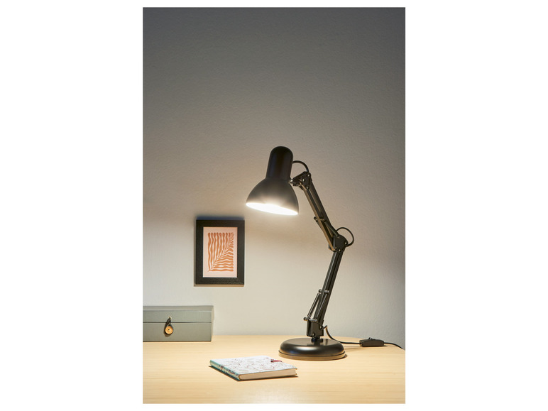 Une lampe de bureau noire avec un bras incurvé sur un bureau en bois.