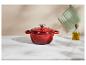 Cocotte en fonte rouge, manique verte et bouteille d'huile d'olive sur un comptoir en marbre.