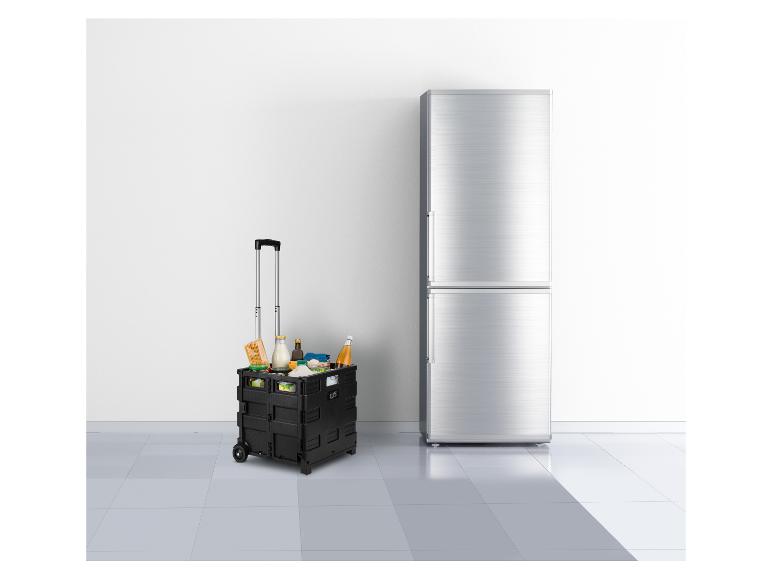 Chariot de courses pliable noir avec des provisions à côté d'un réfrigérateur argenté.