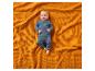 Bébé en tricot bleu sur une couverture gaufrée orange.