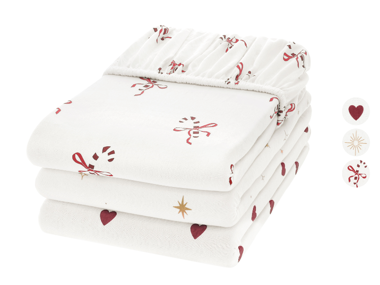 Pile de draps-housses blancs avec cœurs rouges, étoiles dorées et motifs de cannes à sucre.
