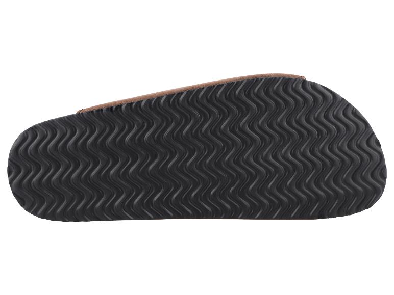 Dessous d'une semelle de sandale noire avec motif ondulé et bordure marron.