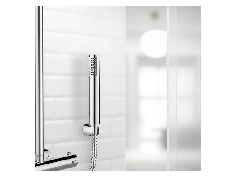 Ensemble de douche chromé avec pomme de douche à main, fixé sur un mur de carrelage blanc.