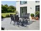 Ensemble de mobilier de jardin avec table et chaises noires sur une terrasse, entouré de verdure.