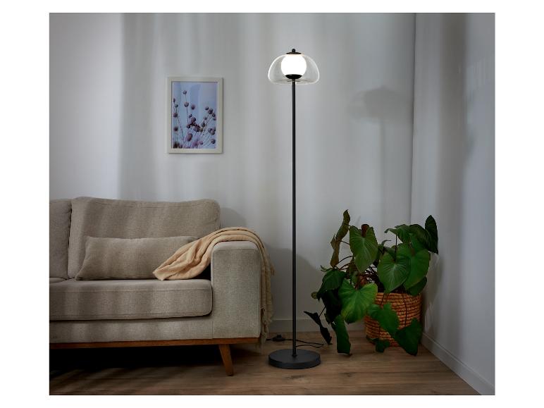 Un lampadaire noir avec un abat-jour en verre dans un salon.