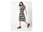 Modèle en robe noire à motif blanc et sandales noires.