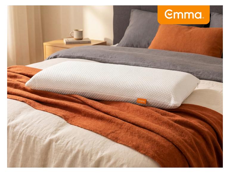 Oreiller blanc texturé sur une couverture orange et une literie grise dans une chambre