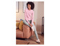 Une femme portant un pull rose et un jean bleu est assise sur un canapé en cuir.