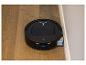 Aspirateur robot noir avec fonction serpillière, marqué 'TruEdge', sur un parquet près d'un mur.