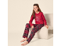 Fille en pyjama rouge avec imprimé 'Let's have breakfast' et pantalon à carreaux, assise sur une chaise.