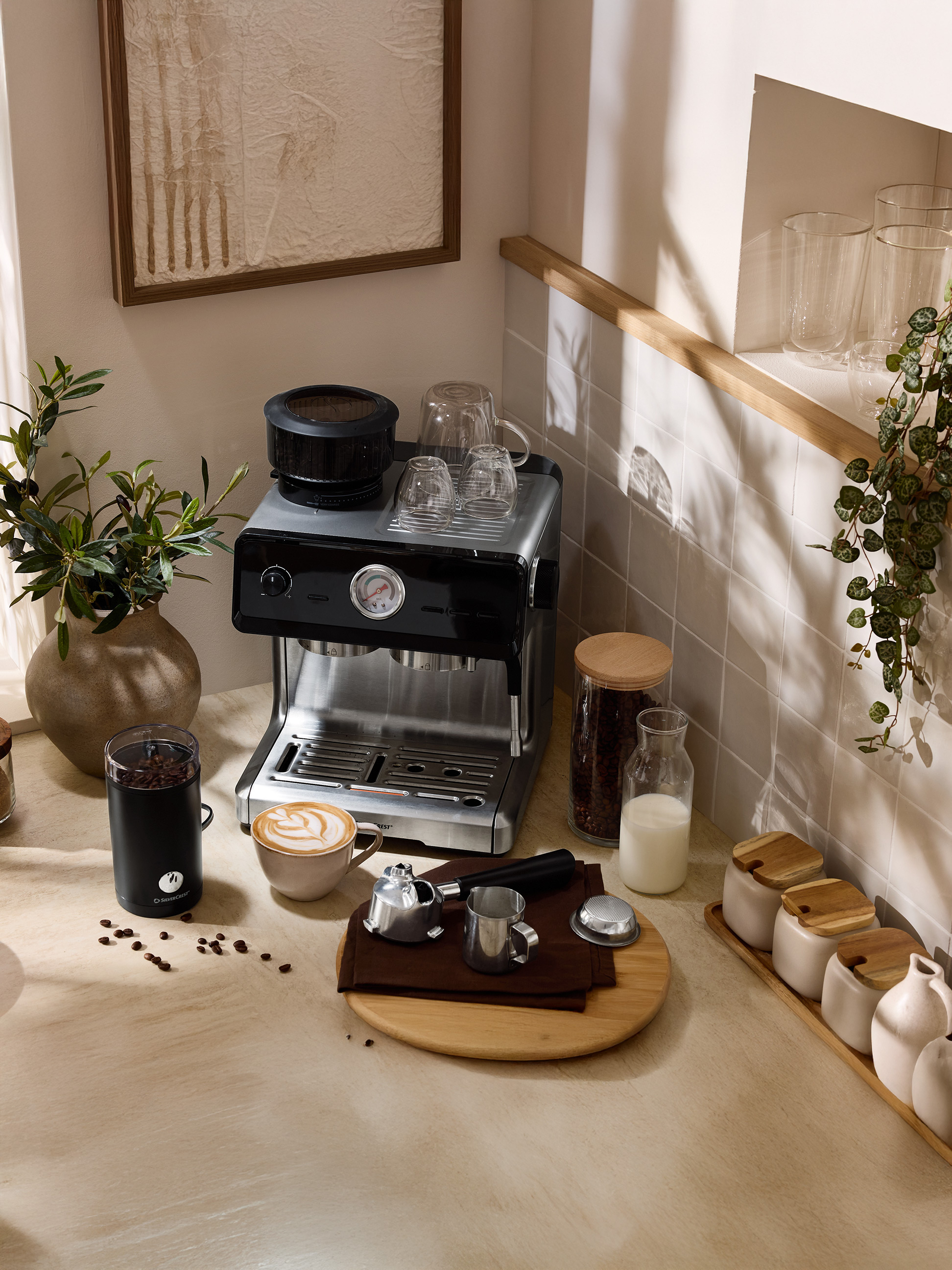 Machine à café avec moulin, tasse de café latte et accessoires sur un comptoir de cuisine.