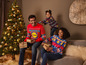 Une famille en pulls de Noël avec le logo Lidl, avec des cadeaux de Noël et un sapin de Noël.