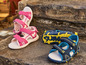 Deux paires de sandales pour enfants, roses avec des cœurs et bleues avec des accents jaunes.