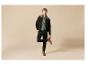 Homme en veste vert foncé, pull vert clair, pantalon noir et bottes marron.