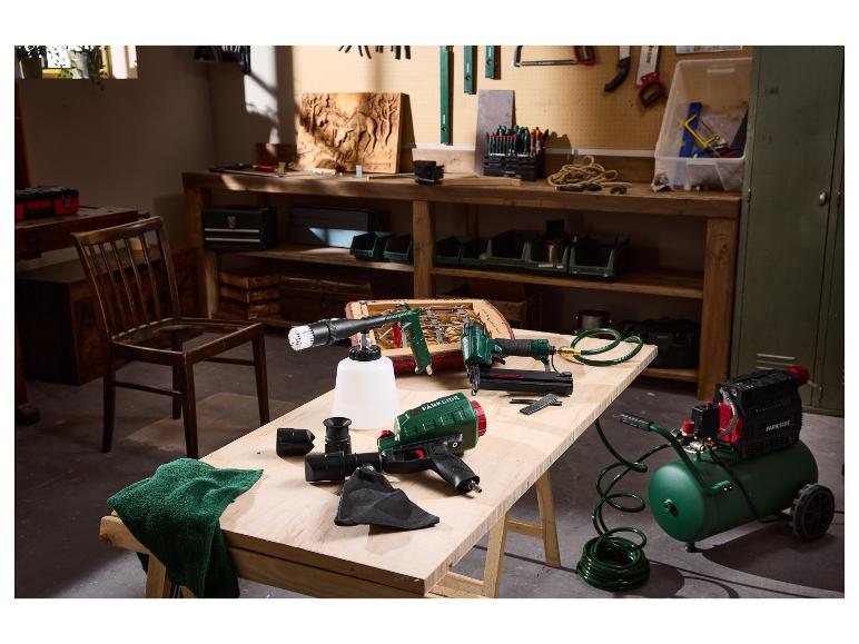 Outils pneumatiques Parkside, dont un compresseur, un pistolet à clous et un pistolet de nettoyage, sur un établi.