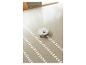 Un aspirateur robot blanc sur un sol clair, laissant des chemins de nettoyage à motifs.