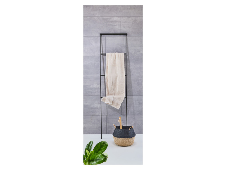 Un porte-serviettes noir avec une serviette et un panier noir et beige.