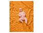 Bébé en pyjama rose à étoiles, allongé sur une couverture gaufrée orange.