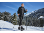 Femme en veste noire et leggings avec bâtons dans un paysage de montagne enneigé