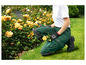 Une personne agenouillée dans le jardin avec des genouillères et des gants Parkside.