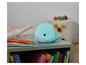 Une lampe de nuit en forme de baleine bleue avec une lumière douce sur une table avec des crayons de couleur et des livres.