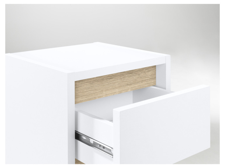 Une table de chevet blanche avec deux tiroirs, dont un est ouvert.