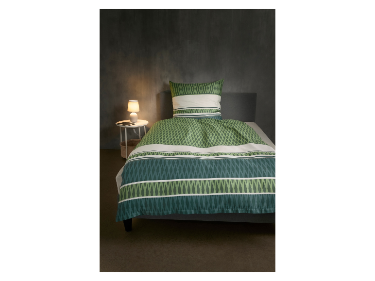 Parure de lit verte et blanche à motifs sur un lit.