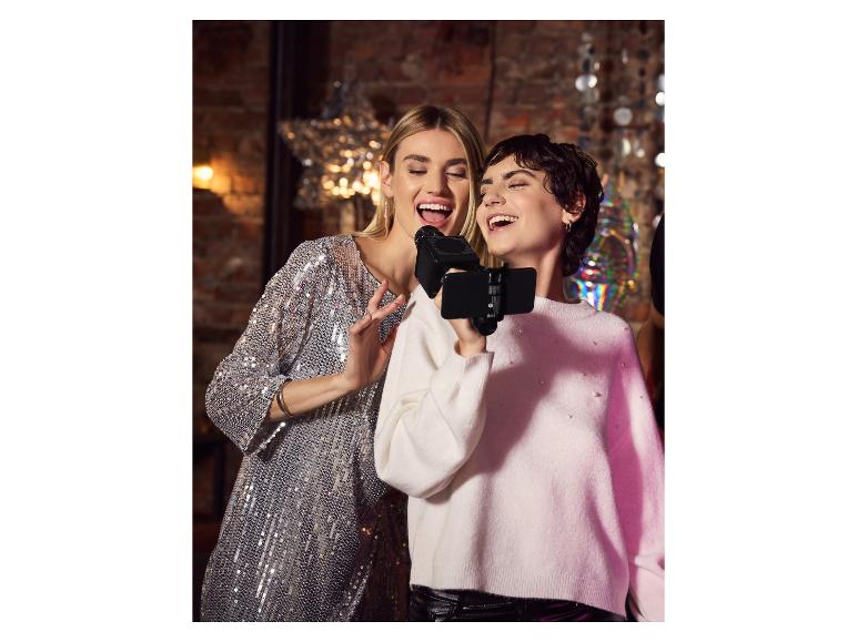 Deux femmes chantant au karaoké avec un microphone et un smartphone lors d'une fête.
