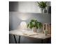Lampe de table blanche sur un bureau en bois avec plantes et livres.
