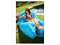 Femme se relaxant sur un fauteuil gonflable bleu près d'une piscine.