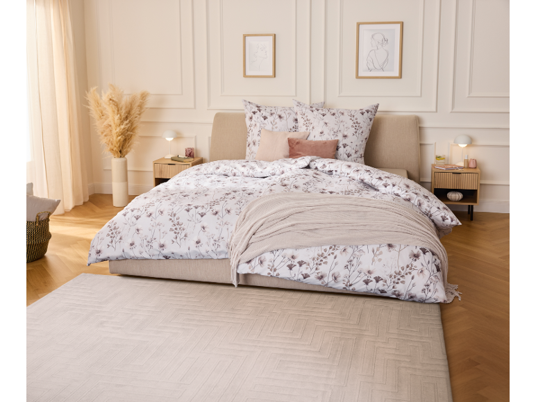 Chambre élégante avec parure de lit fleurie, jeté de lit en tricot et tapis assorti