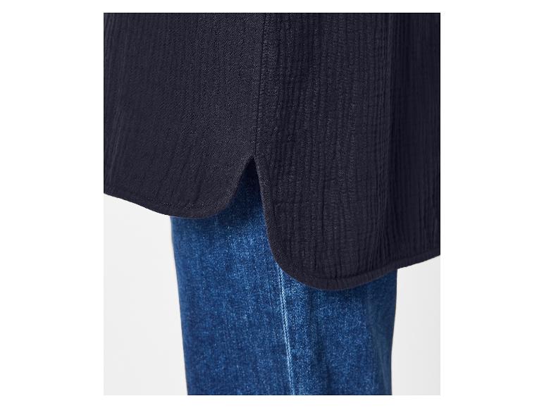 Gros plan d'un chemisier bleu foncé avec ourlet arrondi et fente, porté sur un jean.