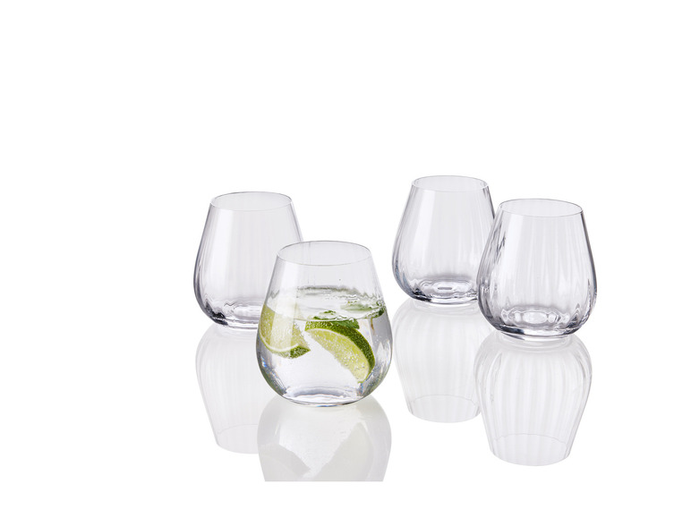 Quatre verres, dont un avec de l'eau et une tranche de citron vert.