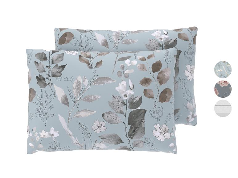 Deux oreillers bleus avec des motifs floraux gris et blancs.
