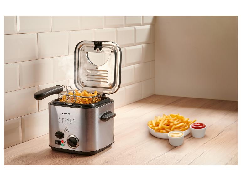 Friteuse avec frites et sauces sur un comptoir en bois.