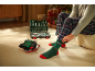 Homme en pantalon de pyjama à carreaux enfilant des chaussettes de Noël vertes à côté d'une boîte à outils.