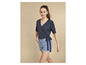 Une femme porte un haut noir à enrouler et un short en jean bleu avec un motif floral.